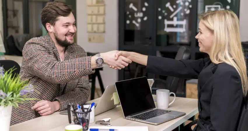 Business professionals shaking hands in a modern office.