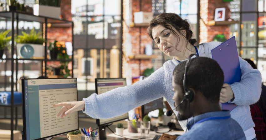 Manager guiding call center agent on CRM system